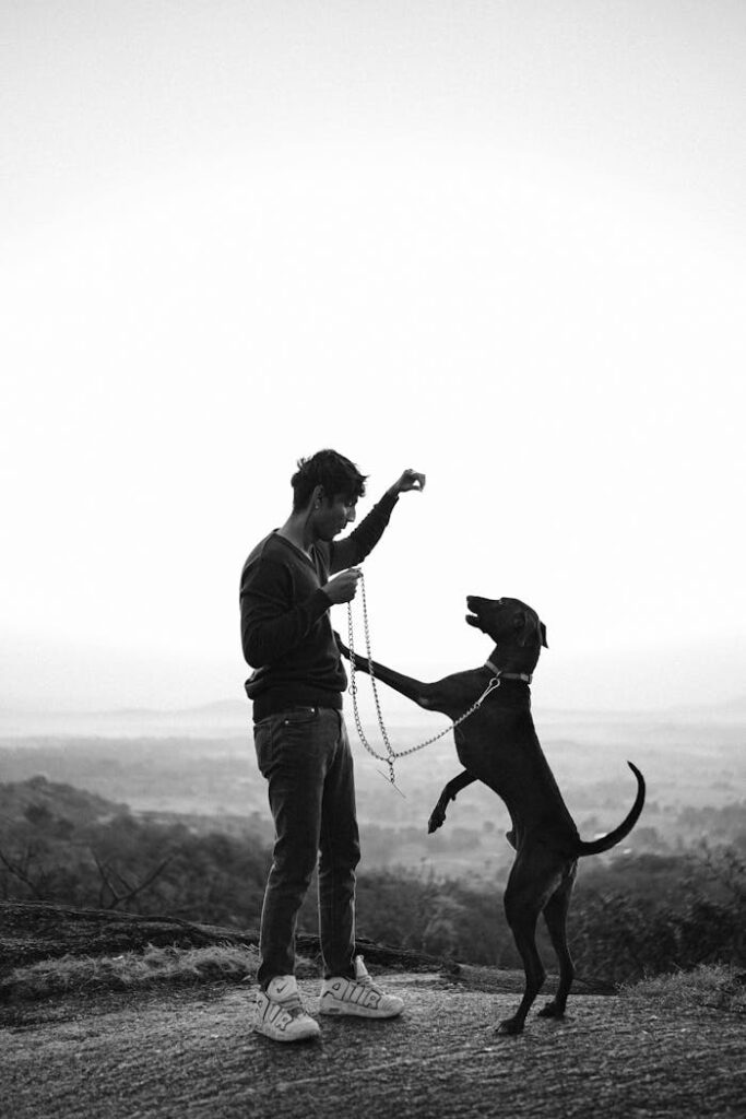 Black and white image of a man playing with his dog in rural Khanapur, India.